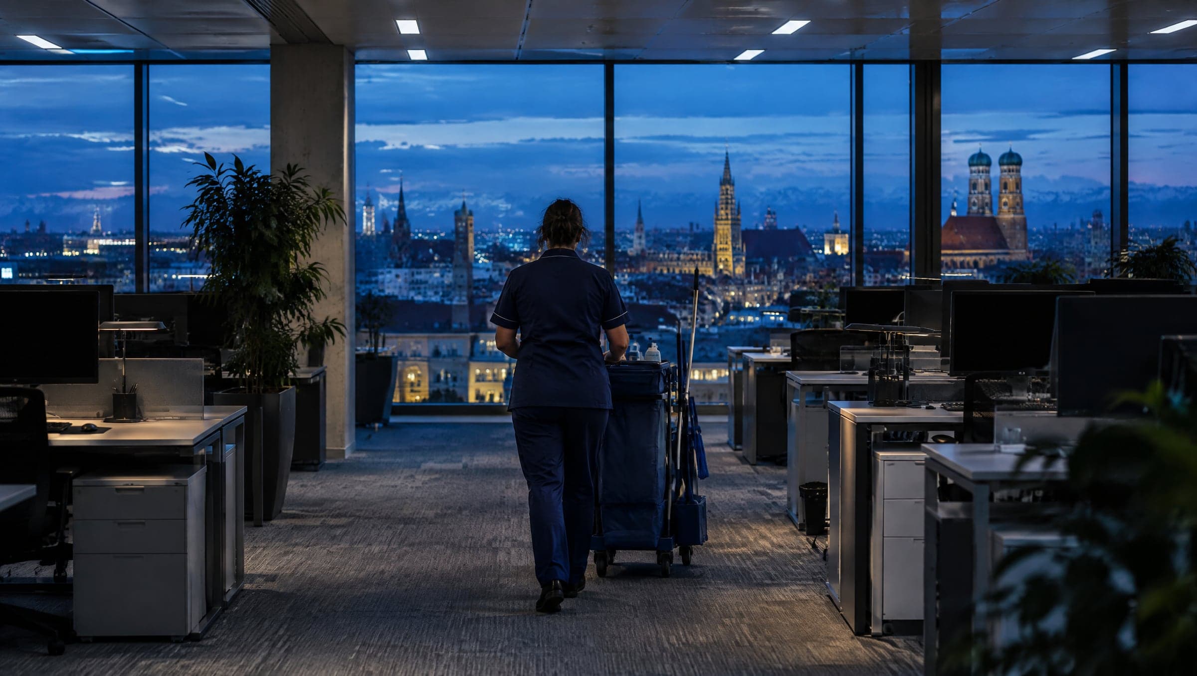 Reinigungskraft schiebt am Abend einen Reinigungswagen durch ein Münchner Büro (KI-generiertes Symbolbild)